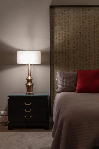 a bedroom with a bed and a lamp on dresser