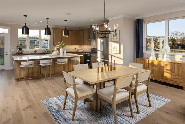 a dining room with stainless steel appliances kitchen island granite countertop a table chairs and a chandelier