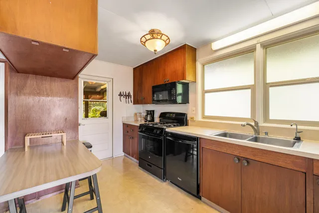 a kitchen with stainless steel appliances granite countertop a sink a stove a microwave cabinets and a dining table