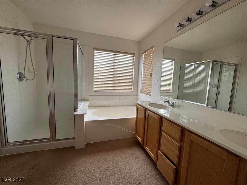 9915 Ridge Hill Avenue Las Vegas, NV 89147 - Photo 16 of 17 Bathroom featuring a shower stall, double vanity, dark carpet, and a garden tub