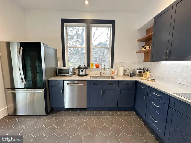 a kitchen with stainless steel appliances granite countertop a refrigerator a sink a stove a washer dryer and a cabinets