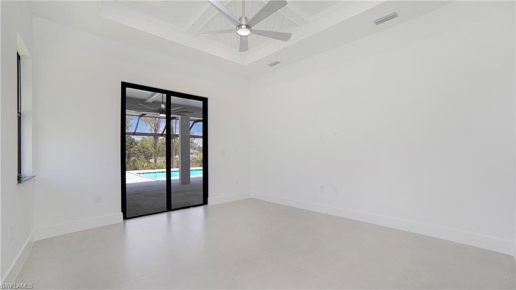 2343 Oil Well Road Naples, FL 34120 - Photo 11 of 46 Spacious room featuring white walls, a coffered ceiling with a ceiling fan, and light-toned flooring