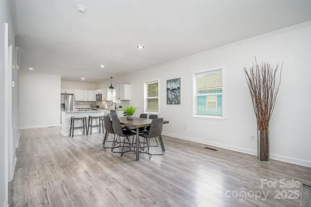 a open kitchen with stainless steel appliances granite countertop a stove top oven a sink dishwasher and white cabinets with wooden floor