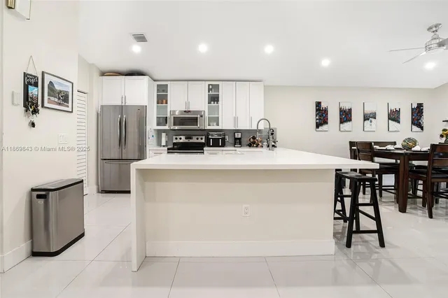 a kitchen with stainless steel appliances a refrigerator a stove a sink a dining table and chairs