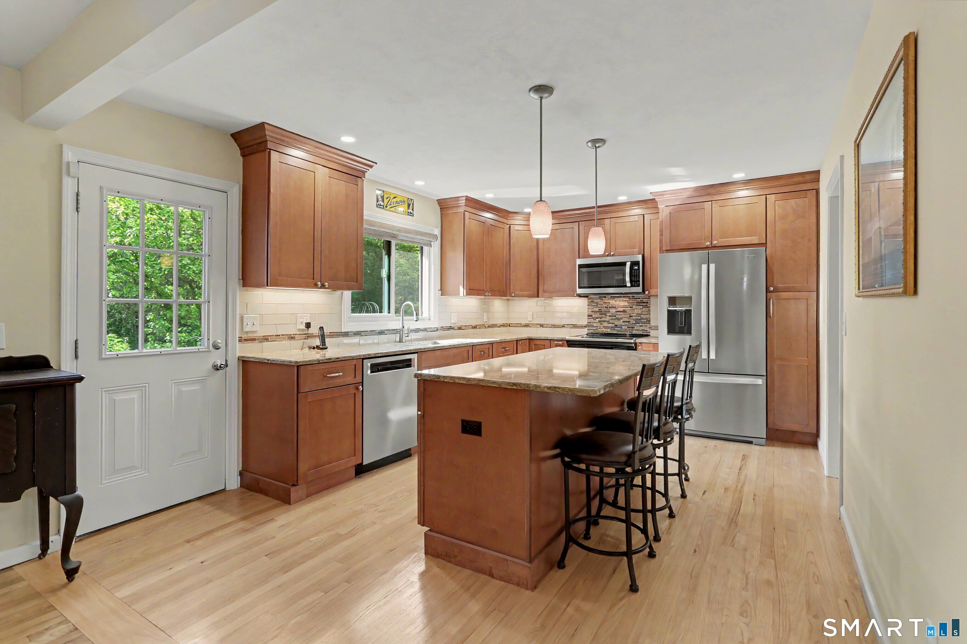 632 Wheelers Farm Road Orange, CT 06477 - Photo 7 of 39 a kitchen with kitchen island granite countertop wooden floors appliances and furniture