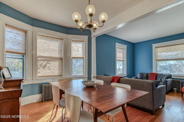 a dining room with wooden floor a chandelier a wooden table and chairs