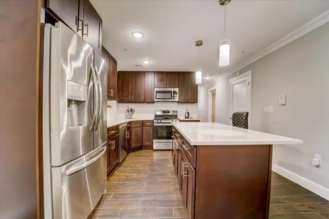 a kitchen with stainless steel appliances granite countertop a refrigerator a sink dishwasher a stove oven and white countertops with wooden floor