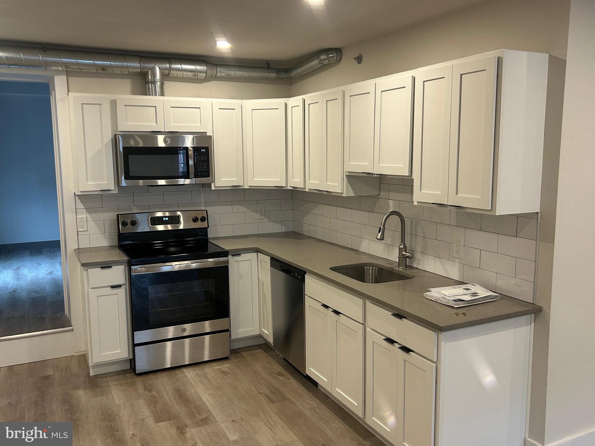 224 Hall Street, Unit 8 Phoenixville, PA 19460 - Photo 2 of 16 a kitchen with stainless steel appliances granite countertop a sink a stove a microwave and cabinets