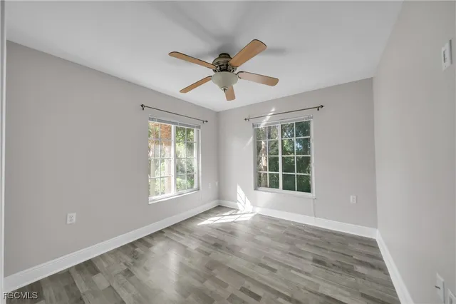 a view of an empty room with window and chandelier fan
