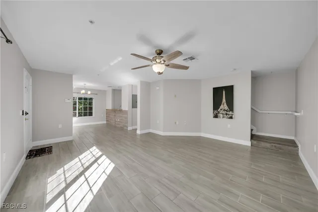 an empty room with wooden floor and ceiling fan