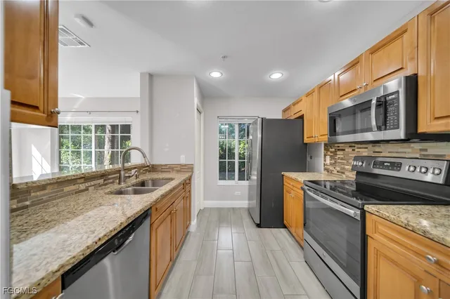 a kitchen with stainless steel appliances granite countertop a stove a sink and a microwave