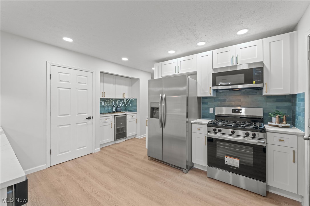 5266 Wilson Mills Road Cleveland, OH 44143 - Photo 18 of 50 Kitchen featuring stainless steel appliances, white cabinets, light wood-style floors, beverage cooler, and recessed lighting