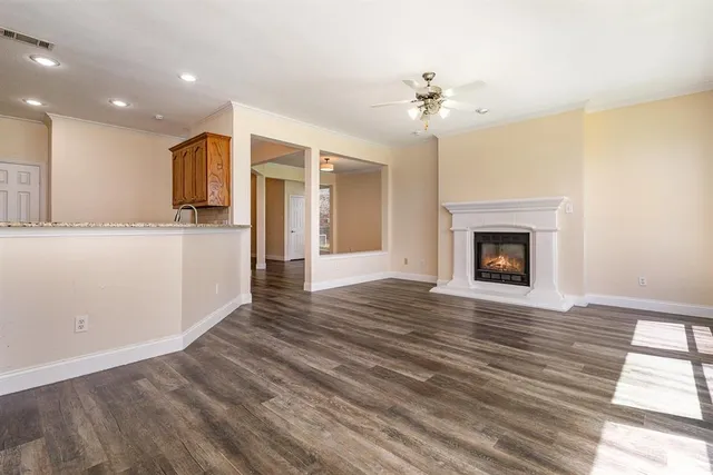 a view of an empty room with wooden floor and a fireplace