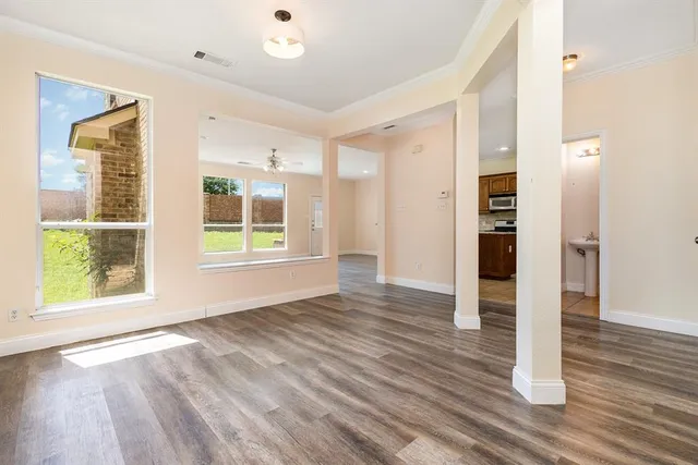 a view of an empty room with wooden floor and a window
