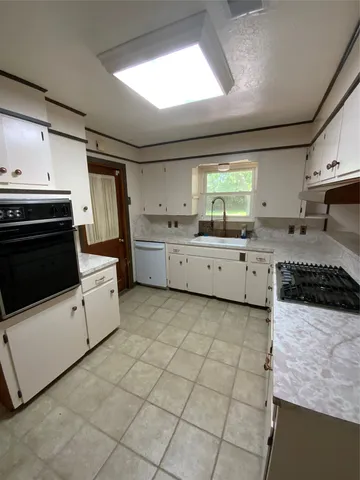 a kitchen with granite countertop a stove sink and cabinets