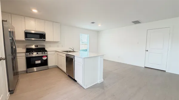 a kitchen with stainless steel appliances a stove a microwave a sink and cabinets