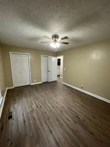 an empty room with wooden floor and a ceiling fan