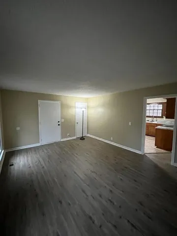 an empty room with wooden floor cabinet and windows