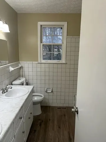 a bathroom with a granite countertop toilet a sink and a mirror