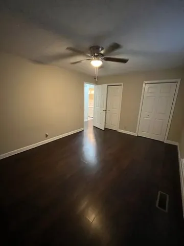 an empty room with wooden floor and fan