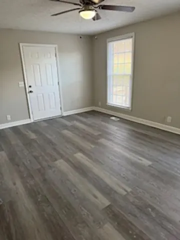an empty room with wooden floor and windows