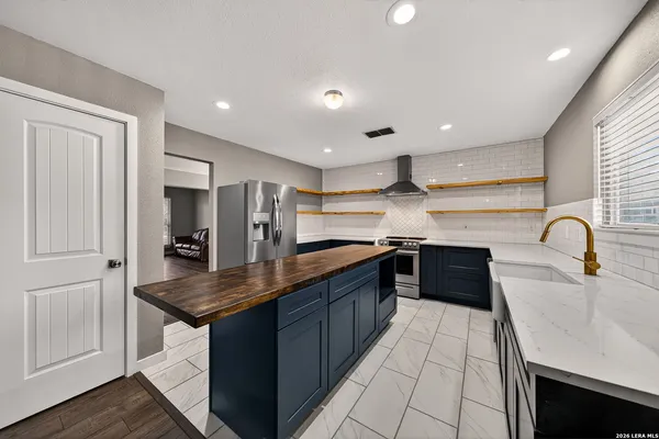 a kitchen with stainless steel appliances granite countertop a sink dishwasher and a refrigerator with wooden cabinets