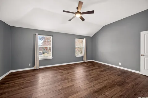 an empty room with wooden floor fan and windows