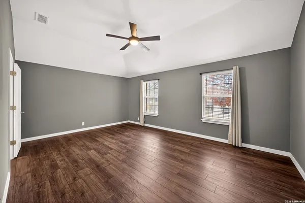 a view of empty room with wooden floor and fan