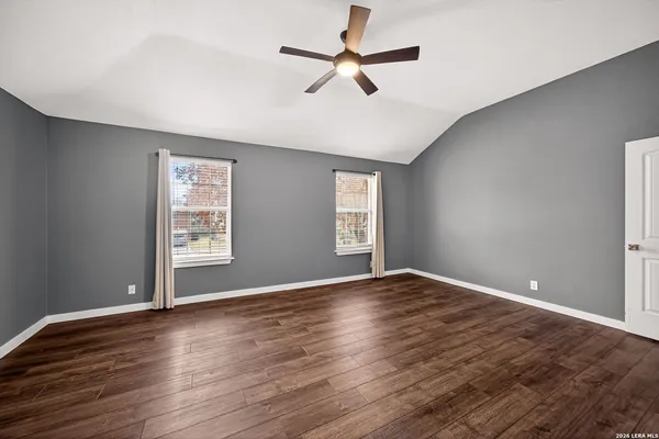 an empty room with wooden floor fan and windows