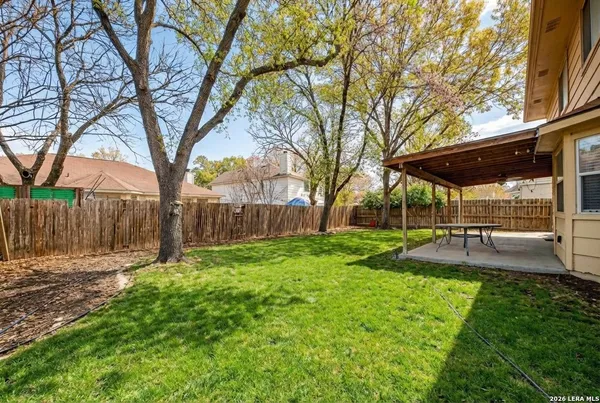 a view of a backyard with table and chairs under a large tree
