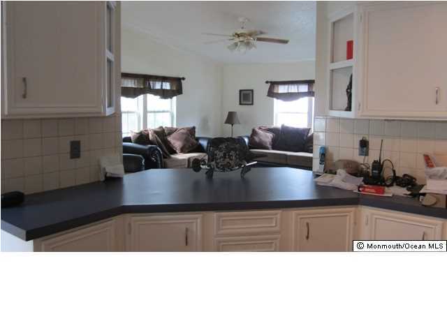 88 Village Road Morganville, NJ 07751 - Photo 6 of 10 a kitchen with stainless steel appliances granite countertop a sink dishwasher white cabinets and couches with wooden floor