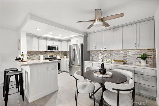 a kitchen with stainless steel appliances kitchen island granite countertop a dining table chairs refrigerator and microwave