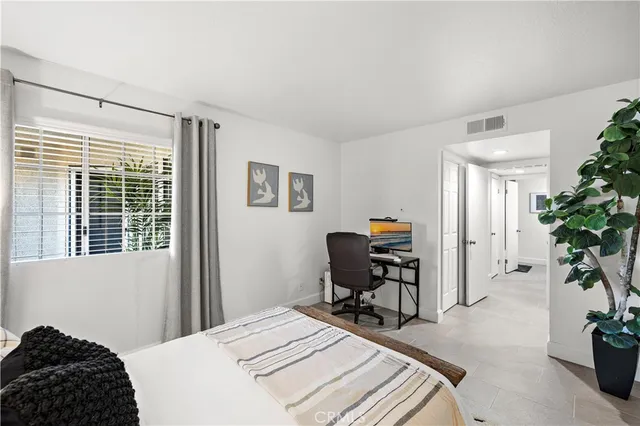 a bedroom with a bed table chair and a potted plant