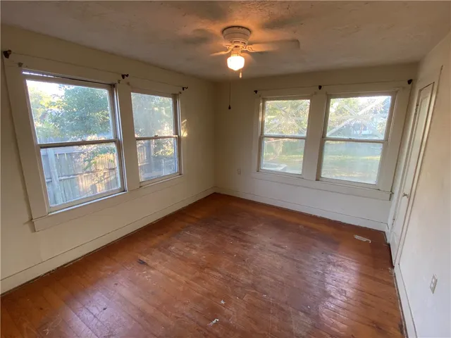 a view of an empty room with a window and wooden floor