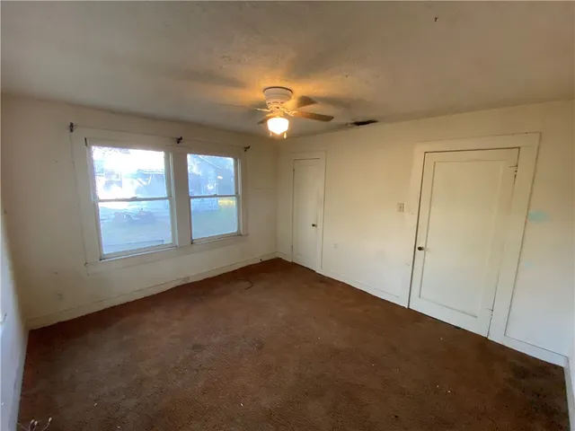 an empty room with windows and fan