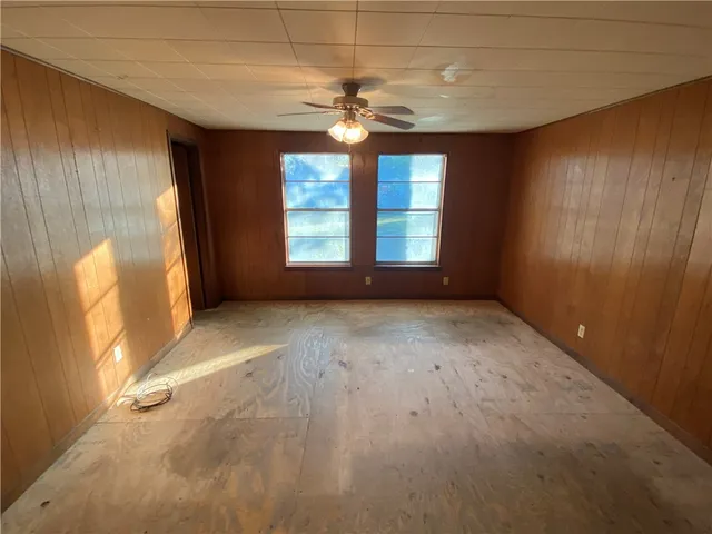 an empty room with windows and chandelier fan