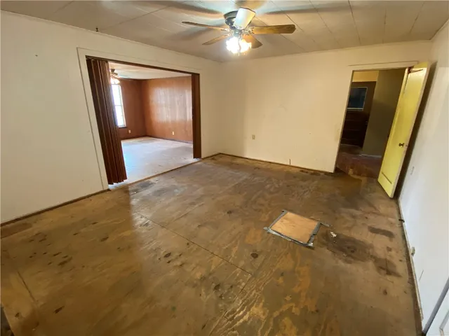 en empty room with wooden floor and fan
