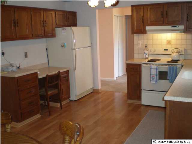 99 Evesham Road, Unit A Freehold, NJ 07728 - Photo 2 of 3 a kitchen with a refrigerator a stove top oven a sink and cabinets