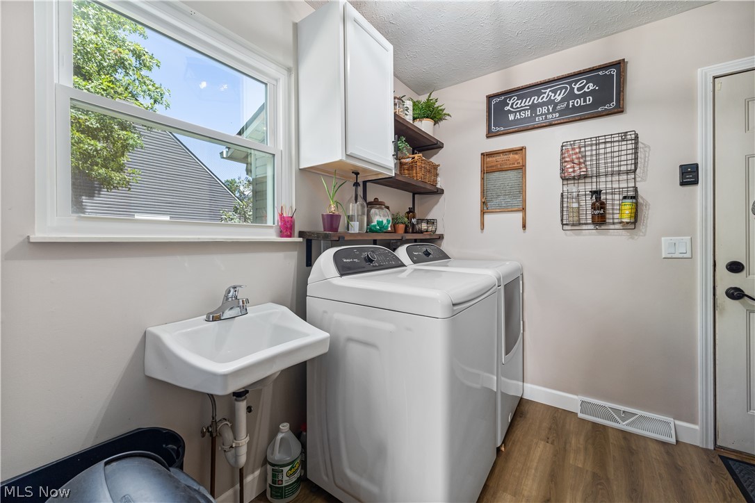 684 Guilford Road Vermilion, OH 44089 - Photo 18 of 37 Laundry room with a textured ceiling, dark hardwood / wood-style flooring, washing machine and dryer, cabinets, and sink