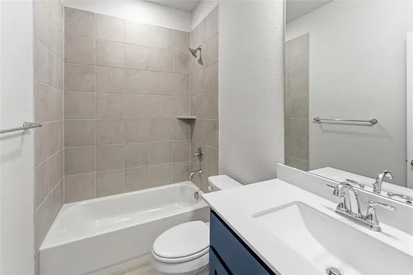 a bathroom with a bathtub shower sink vanity mirror and toilet