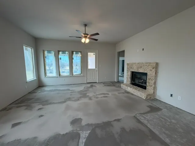 an empty room with windows and fireplace