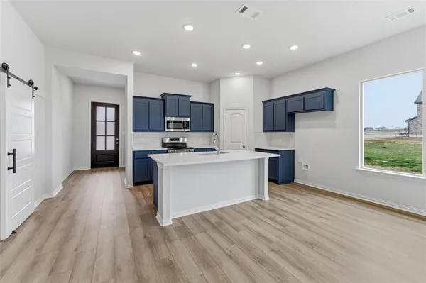 a view of kitchen with microwave a refrigerator and wooden floor