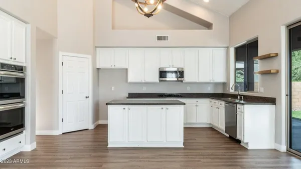 a kitchen with stainless steel appliances a sink stove and wooden floor