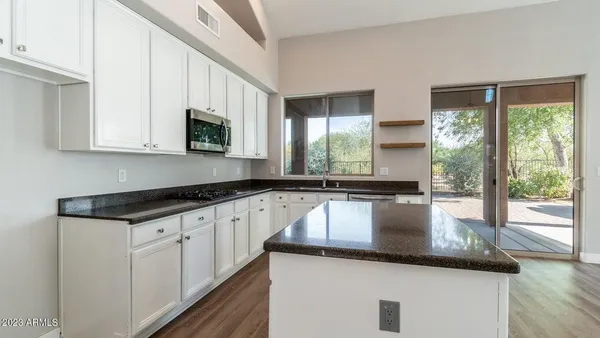 a kitchen with kitchen island granite countertop a sink a counter top space and cabinets