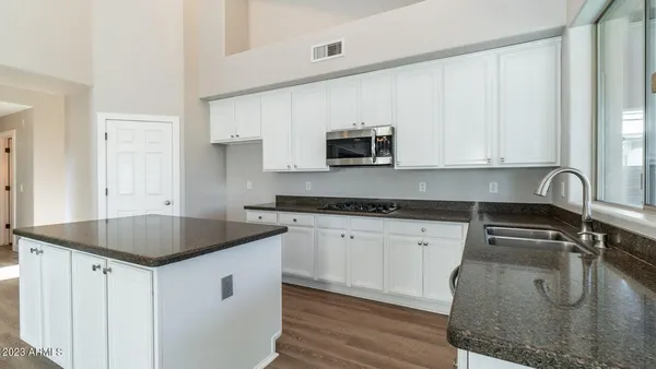 a kitchen with granite countertop a sink a stove and cabinets