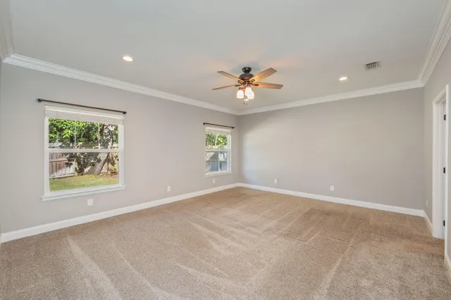 an empty room with windows and ceiling fan