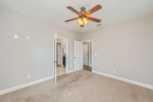 an empty room with a chandelier fan and closet area