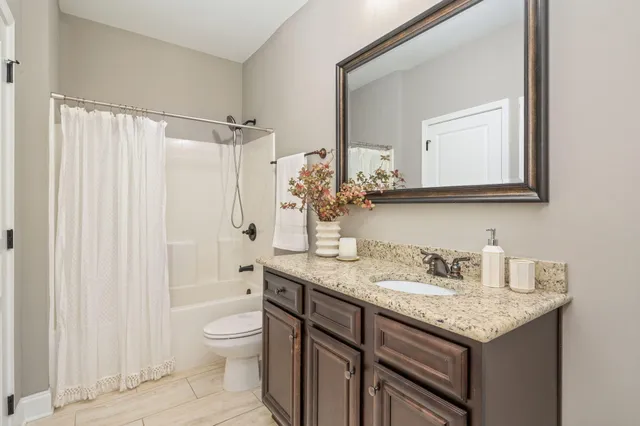 a bathroom with a granite countertop sink toilet a mirror a bathtub and shower