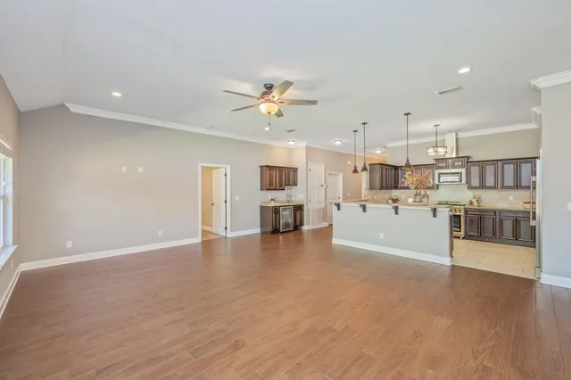 a view of a kitchen with kitchen island wooden floor and stainless steel appliances
