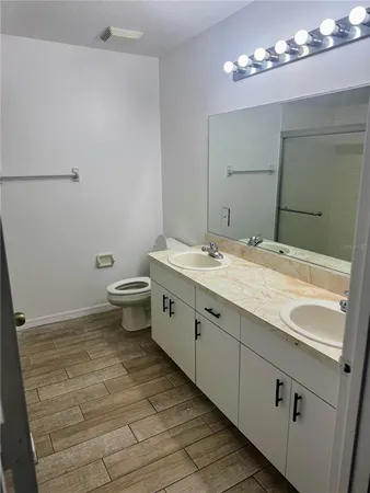 a spacious bathroom with a double vanity sink a toilet and a mirror